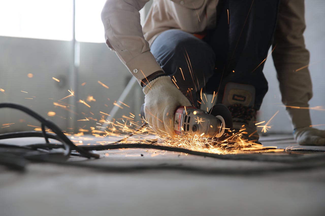 why-choose-us A skilled industrial worker uses a grinder creating a burst of sparks indoors.
