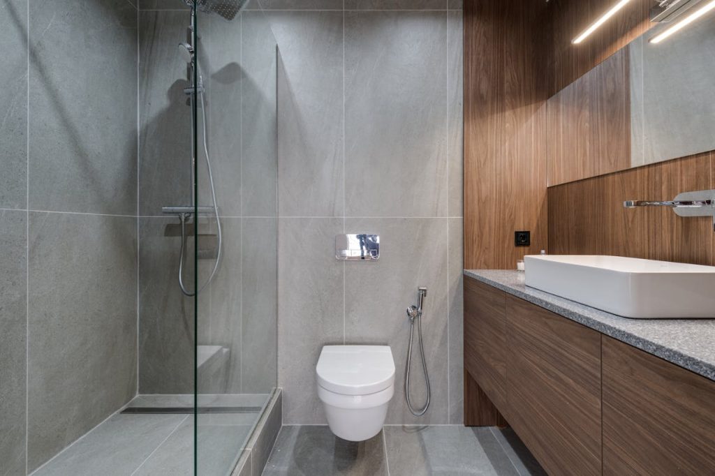 pexels photo 7614405 Elegant modern bathroom featuring a walk-in shower, sink, and toilet with a stylish wooden finish.